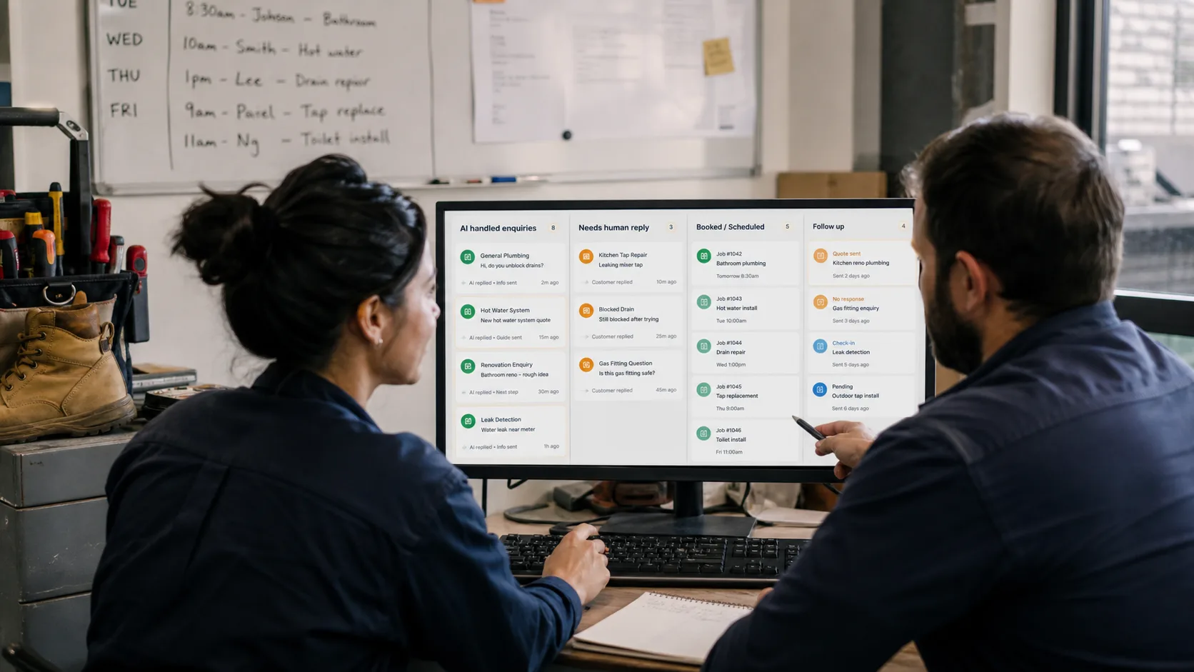 Two team members reviewing a shared inbox dashboard with AI replies, human-reply column, and booked jobs.